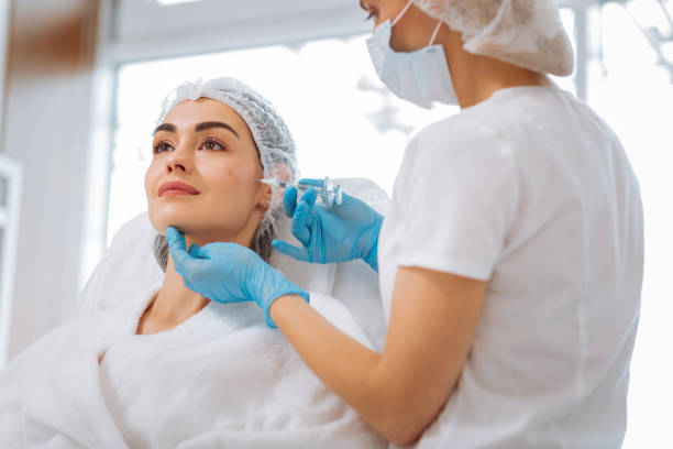 istock Skilled female cosmetologist doing an injection in the cheek 1027009018