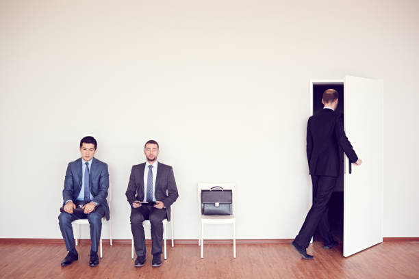 istock Serious candidates for job sitting on chairs while waiting for their turn, bald man coming office room 1027016908