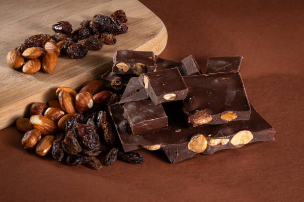 istock Stack of dark chocolate pieces with roasted almonds and raisins 1027027236
