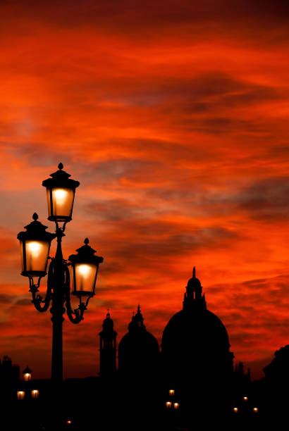 Beautiful sunset over Salute Basilica (Saint Mary of Health) domes with old street lamps in Venice