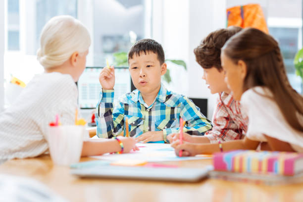 istock Smart schoolboy telling a story to his classmates 1027037386