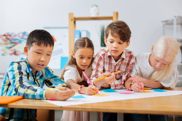 istock Concentrated kids drawing a bright poster in a class 1027039770