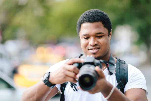 An African tourist is checking the photos in his camera during his travel.