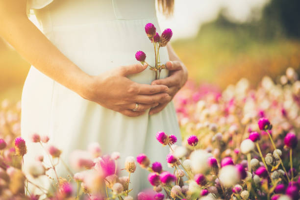 Flower of my life.  Pregnant woman standing in flowers. Close up. Copy space.