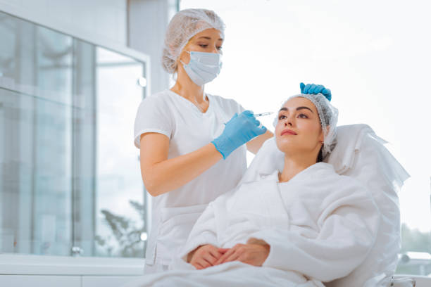 istock Smart skilled beautician standing near her client 1027059532