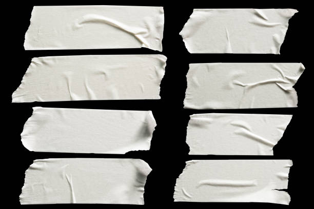 Photo of Set of white scotch tapes on black background. Torn horizontal and different size white sticky tape, adhesive pieces.