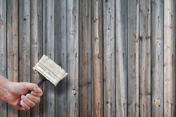 istock man's hand holding paintbrush on wooden wall background, copy space 1027069068