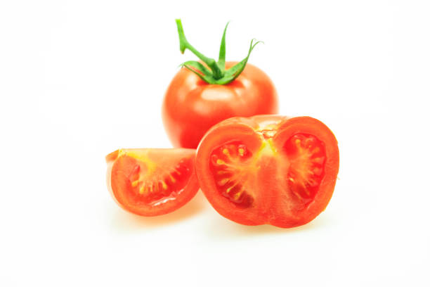 Tomato with stem and one cut in pieces, on white background.
