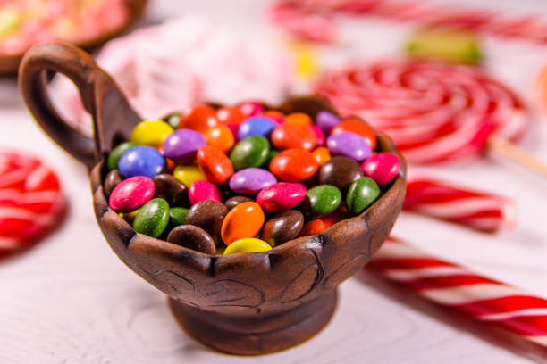 istock Ceramic bowl with colored candies, lollipops and marshmallows on a wooden table 1027088722