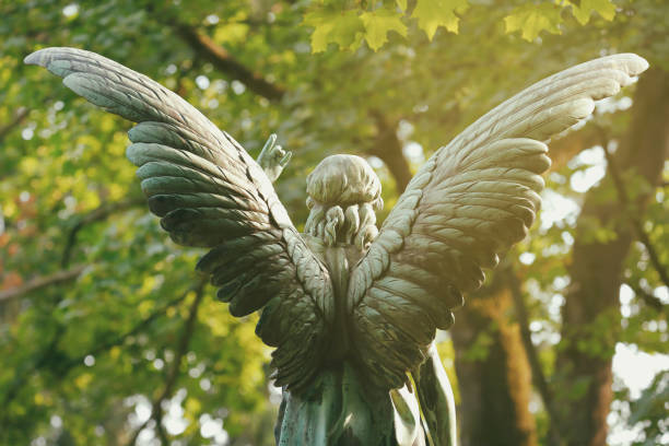 Antique Angel Statue on a Graveyard Weathered old copper angel statue at the Melaten Graveyard, Cologne, Germany hope god lighting technique tree stock pictures, royalty-free photos & images