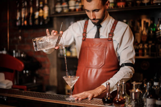 istock Bartender pouring cocktail with an ice cubes into the cocktail glass 1027093128