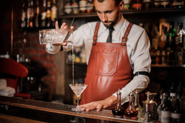 istock Professional bartender pouring cocktail with an ice cubes into the cocktail glass 1027093278
