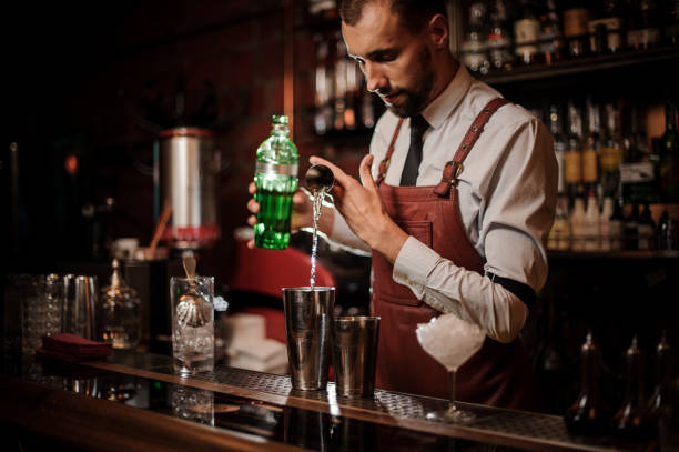 barista versando un alcol dal misurino in uno shaker d'acciaio - cocktail transparent cocktail shaker glass foto e immagini stock
