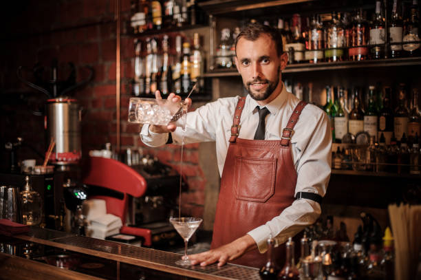 istock Smiling bartender pouring a transparent cocktail into the cocktail glass 1027093412