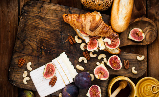 breakfast. a croissant with figs and honey. brie cheese and nuts. wooden board. Vintage background. brown photo. family breakfast. homemade baking