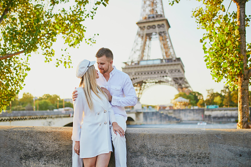 Happy couple near the Eiffel tower. Tourists enjoying their vacation in France. Romantic date or traveling couple concept