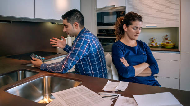 istock Angry couple sitting back to each other after a quarrel by debts 1027100718