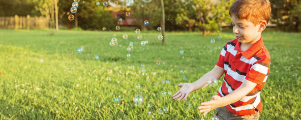istock Happy boy playing with soap bubbles in the park 1027100746