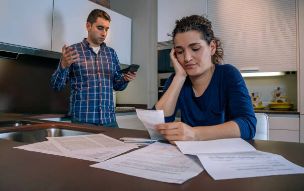 istock Desperate young couple with debts reviewing their bills 1027100752