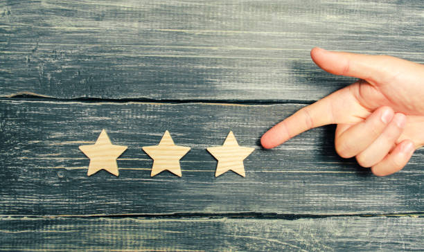 istock Universal recognition, success and high efficiency. Evaluation of the hotel or restaurant. Application in the market. The hand points to the third star on a dark background. Rating, level of quality. 1027108302