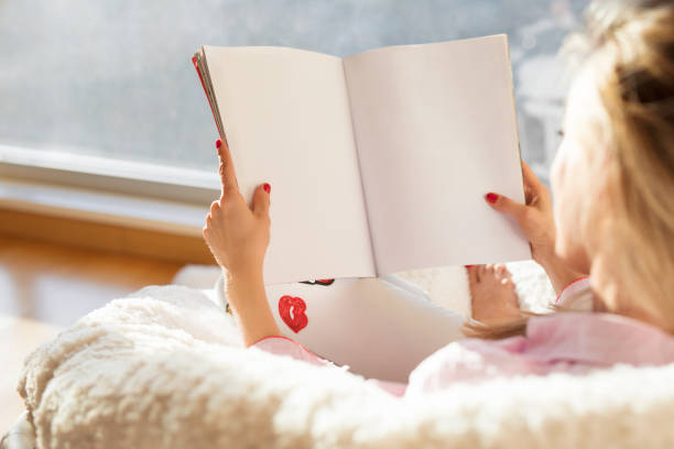 Woman reading magazine with empty white blank pages. Mockup and template for your own content.