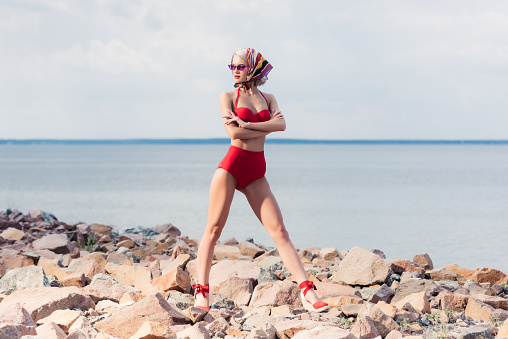 slim stylish girl posing in vintage red bikini on rocky beach