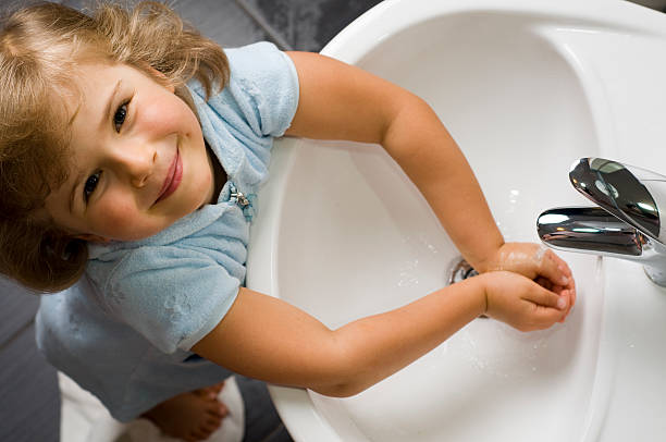 Young girl washing hands while looking up stock photo