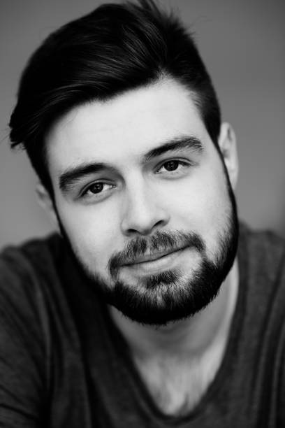 istock Portrait of content handsome simple guy with beard and mustache looking with calmness at camera, black and white photo 1027123890