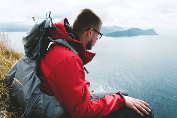 istock Man with backpack rests after hiking and looks at islands in Norway 1027124500