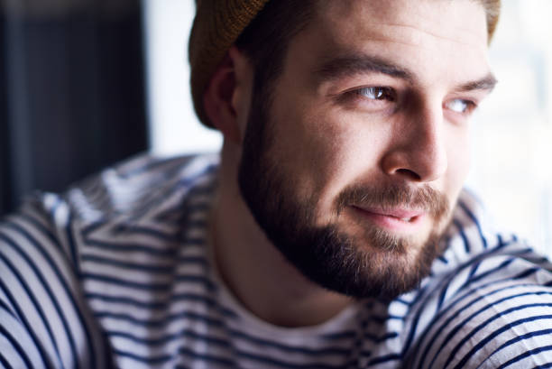 istock Positive content handsome young seaman contemplating outside through window and smiling recollecting life moments 1027124776