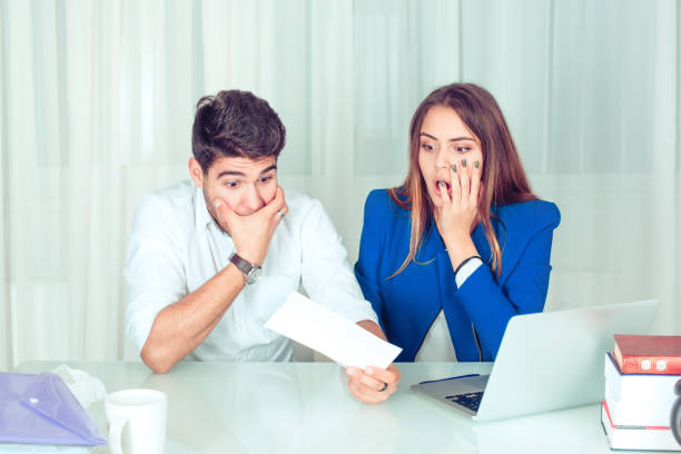 istock Super shocked man and woman watching papers 1027128860