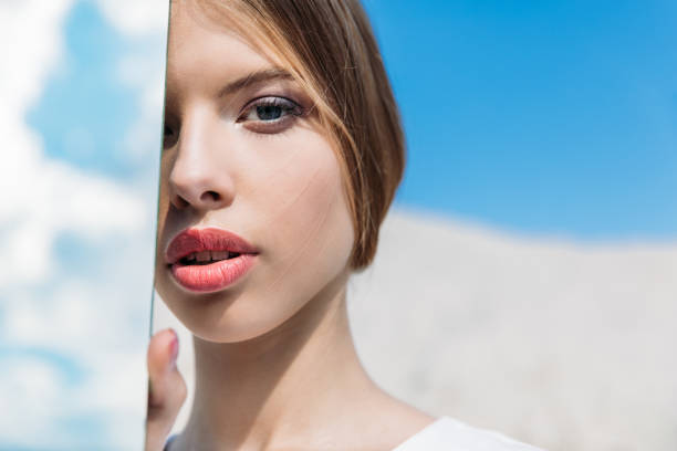 Girl looking in car rear view mirror. This file is cleaned and retouched.