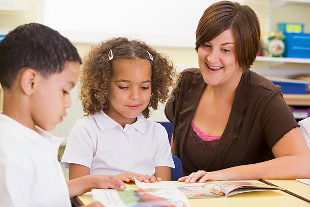 istock Two young children and their teacher reading 102713024