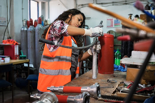 Woman repairing fire extinguisher at workshop
