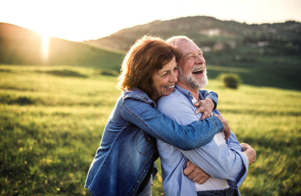 Side view of senior couple hugging outside in spring nature at sunset. Happy senior couple outside in spring nature, hugging at sunset. Side view. senior men stock pictures, royalty-free photos & images