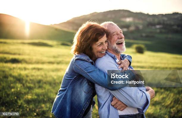 Side View Of Senior Couple Hugging Outside In Spring Nature At Sunset Stock Photo - Download Image Now