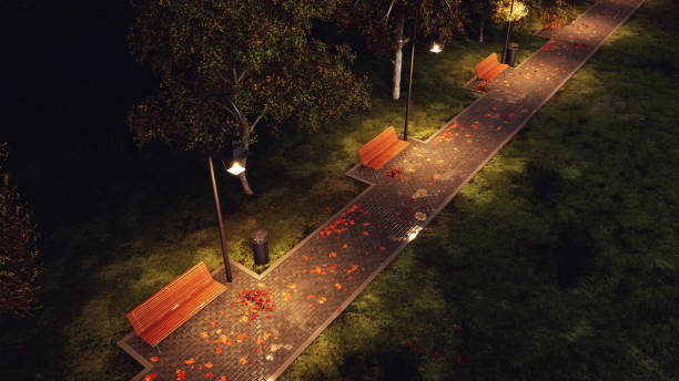 Park walkway lit by street lamps at autumnal night Overhead view of wet after rain park walkway lit by street lamps with empty benches, autumn trees and fallen leaves at dark autumnal night. 3D illustration from my own 3D rendering file. stone bench top view stock pictures, royalty-free photos & images