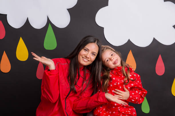 istock A small girl with her mother on a black background with clouds and raindrops. 1027153810
