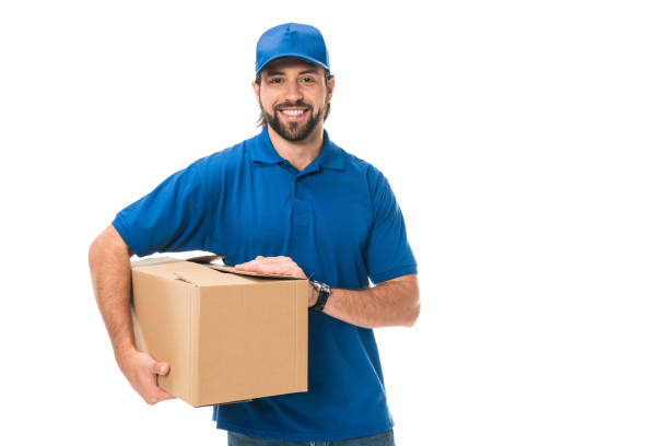 istock handsome young delivery man holding cardboard box and smiling at camera isolated on white 1027154028