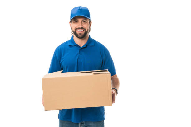 istock handsome happy young delivery man holding cardboard box and smiling at camera isolated on white 1027154150