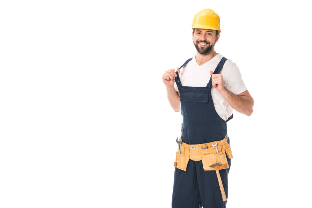 istock handsome happy workman in tool belt and hard hat smiling at camera isolated on white 1027156638