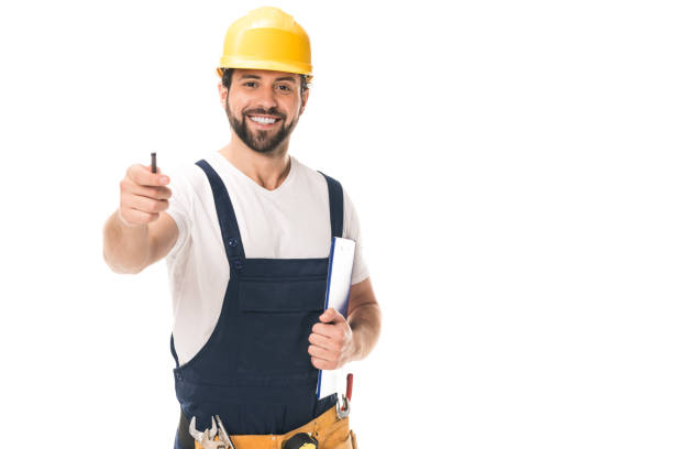 istock handsome construction worker in hard hat holding clipboard and smiling at camera isolated on white 1027157038