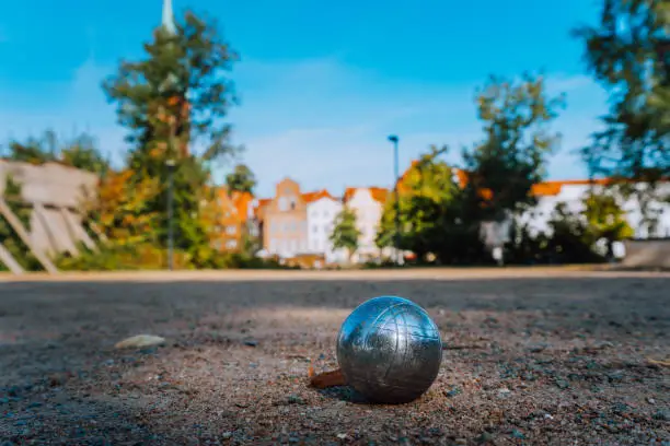 Metall playing ball of petanque game in park with old lübeck city building in blured background. Germany