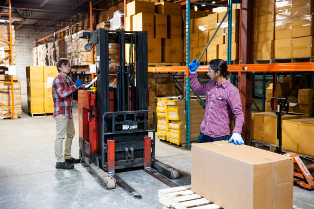 istock Two warehouse workers preparing to lift a heavy box together 1027161740