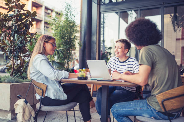 istock College students sitting in a cafe, talking, working on laptop 1027168780