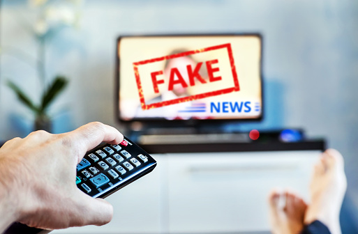 Fake News Propaganda HOAX Political TV Internet Social. young man watching the fake news report on TV at home. Agitation and propaganda in the modern television. switching channel on remote control