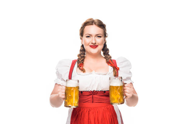 garçonete de oktoberfest sorridente no vestido tradicional alemã, com duas canecas de cerveja light isolado no fundo branco - german culture people women germany - fotografias e filmes do acervo