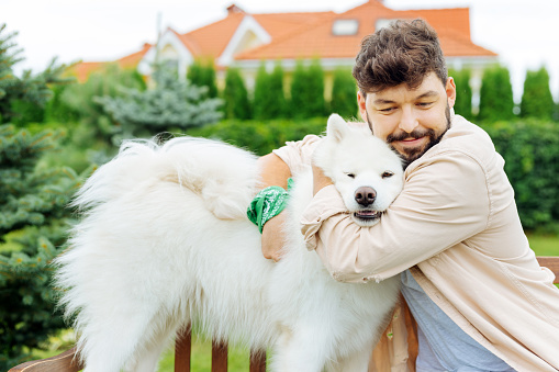 Man and husky. Handsome man and white husky hugging while enjoying freshness of summer day greatly