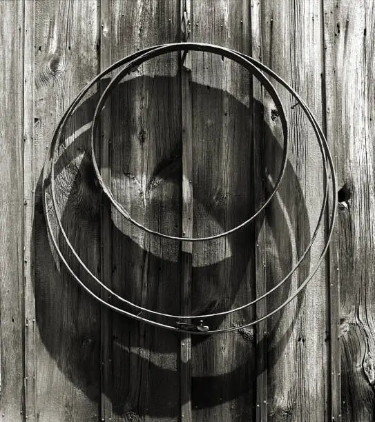 Three rusted and forgotten wagon wheel rims hanging on building