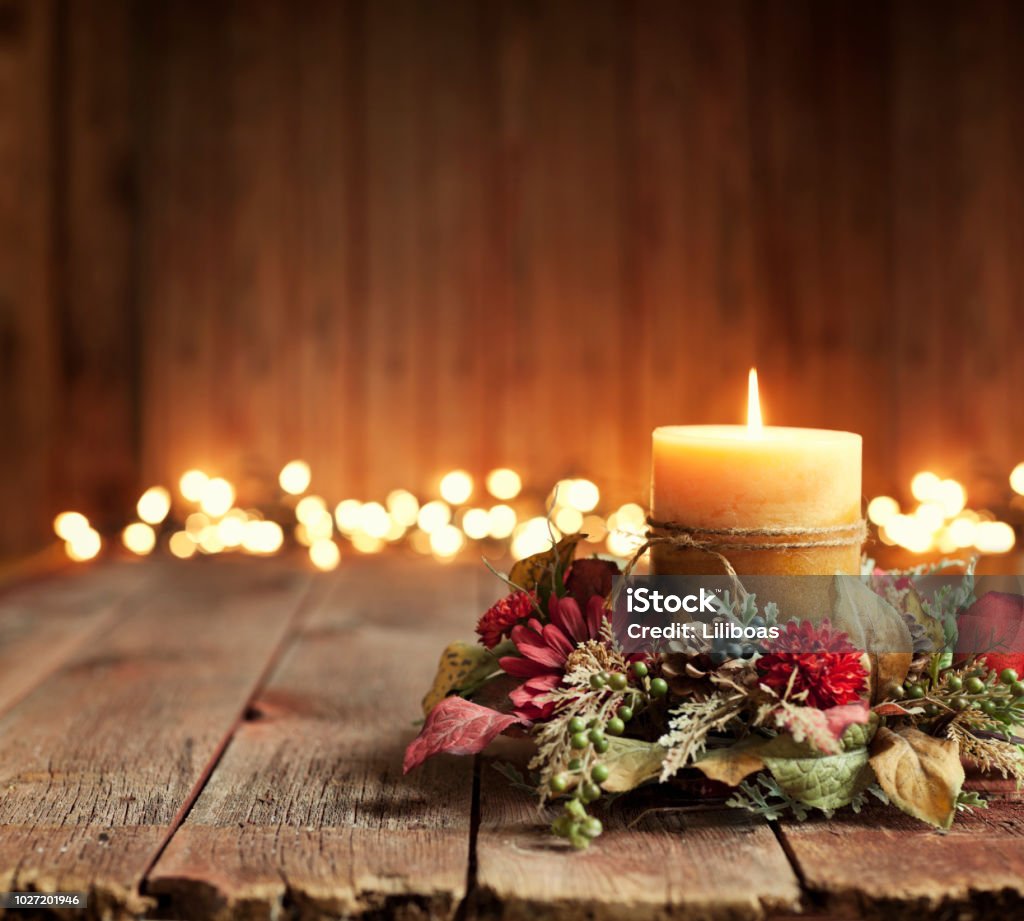 Christmas or Thanksgiving holiday Candle on a Wood Background Christmas holiday elegant candle set against Christmas lights and old textured and toned wood background Christmas Stock Photo